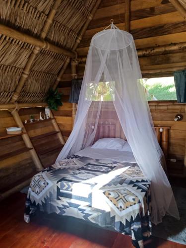a bed in a room with a mosquito net at Cabanas ecologicas con vista espectacular y cascada privada - Finca Qawana Ecolodge en San Carlos in Cristalina