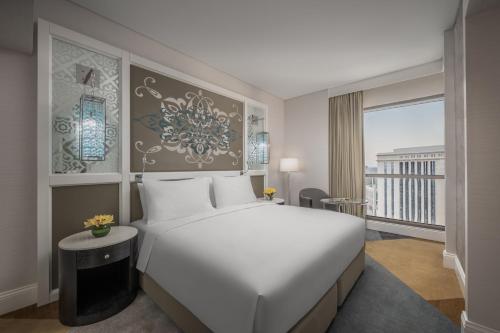a bedroom with a large white bed and a balcony at Rotana Jabal Omar Makkah in Mecca