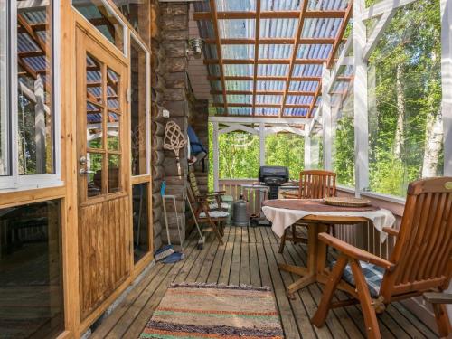 a cabin with a porch with chairs and a table at Holiday Home Lemmenmaja by Interhome in Paatela