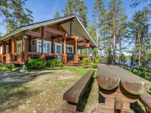 a log cabin with a wooden bench in front of it at Holiday Home Lehtimaja by Interhome in Tiitanvaara