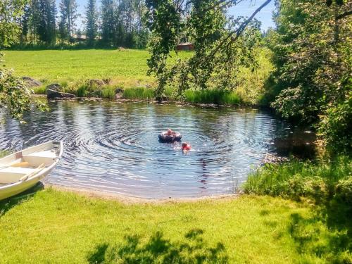 a person swimming in a river with a boat at Holiday Home Sillankorva by Interhome in Korpijärvi