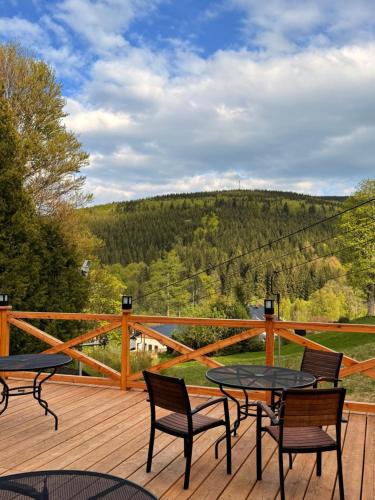 a deck with tables and chairs and a view of a hill at Horský hotel Vidly in Karlova Studánka