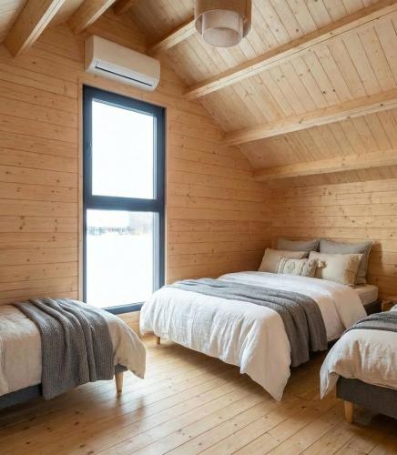 two beds in a room with wooden walls and a window at Domki Lubikowo in Przytoczna 