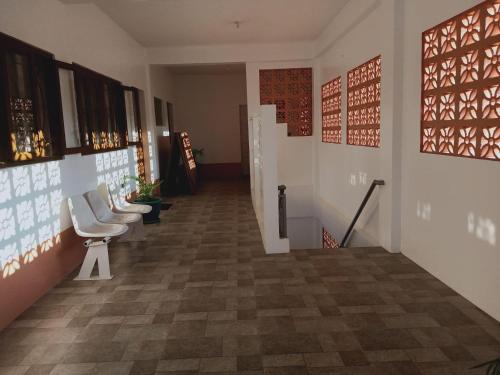a hallway with white chairs and paintings on the wall at Jarens Diner in Silang