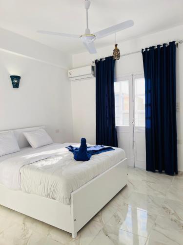 a white bedroom with a bed with blue curtains at Happiness Guest House in Luxor