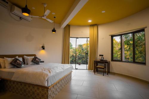 a bedroom with a bed and a desk and windows at Aatman Forest Resort - A Luxury Stay in Sasan Gir in Sasan Gir