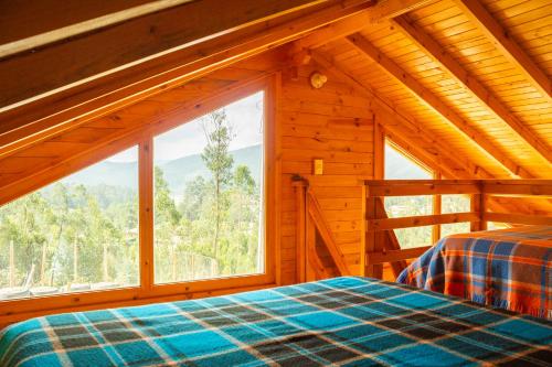 a bedroom with a bed and a large window at Cabañas Tierra Noble in Nobsa