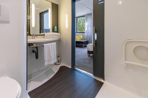 a bathroom with a sink and a toilet and a mirror at Novotel Suites Paris Stade de France in Saint-Denis