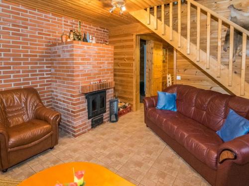 a living room with two leather couches and a brick fireplace at Holiday Home Metsämökki by Interhome in Barkarböle
