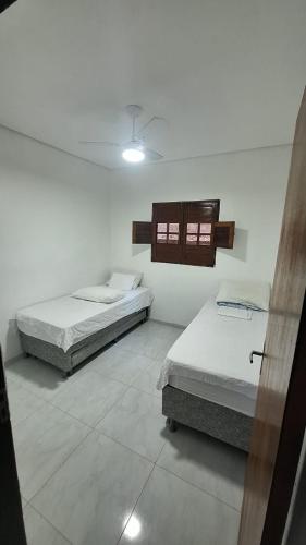 two beds in a white room with at Mirante Rota do Mar in Maceió