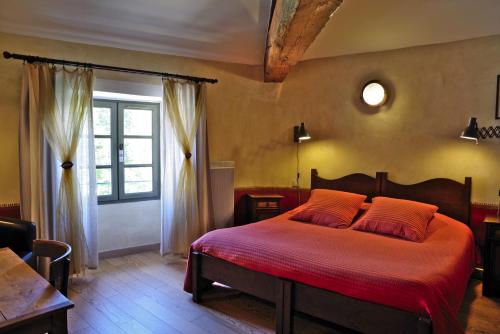a bedroom with a bed with red sheets and a window at Des Lits Sur La Place in Hérépian