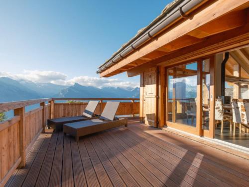 a wooden deck with chairs and a view of mountains at Chalet Chalet Flocon de Neige by Interhome in Nendaz