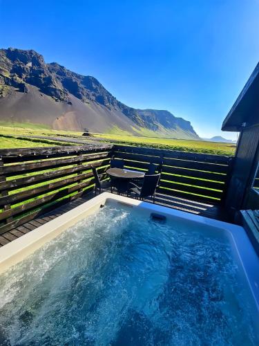 a hot tub with a table and mountains in the background at Aurora Cabin and Private Jacuzzi in Hvolsvöllur