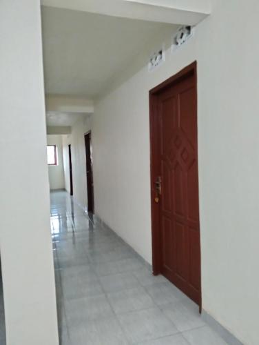 a hallway with a brown door and a tile floor at Penginapan amalia in Soreang