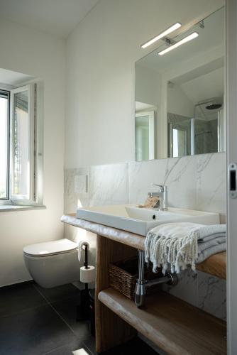 a bathroom with a sink and a toilet and a mirror at Tenuta Dei Vicini - Luxury Apartments in San Marzano Oliveto