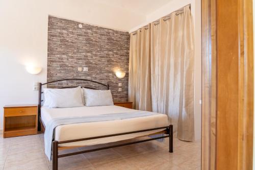 ein Schlafzimmer mit einem Bett und einer Ziegelwand in der Unterkunft Possidi Kouslaka in Posidi