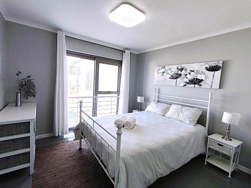 a bedroom with a white bed and a window at Clarke House in Stompneusbaai