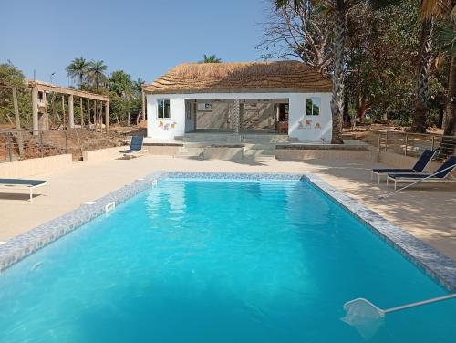 a large blue swimming pool next to a house at Nyantanto Eco Lodge in Gunjur