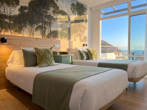 two beds in a room with a large window at Sunset Suites by Bull Hotels in Puerto Rico de Gran Canaria