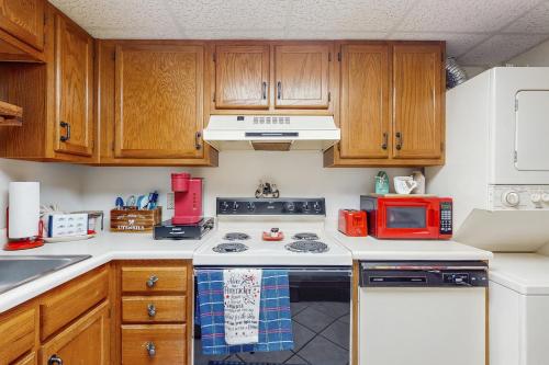 a kitchen with wooden cabinets and a white stove top oven at Delightful Condo Sleeps 6 Shared Pool Picnic Area in Pigeon Forge