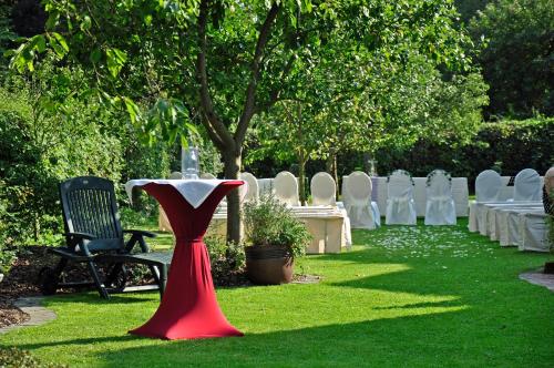 a red vase sitting in the grass with a table and chairs at Hotel & Restaurant Zum Deutschen Hause in Kirchhatten