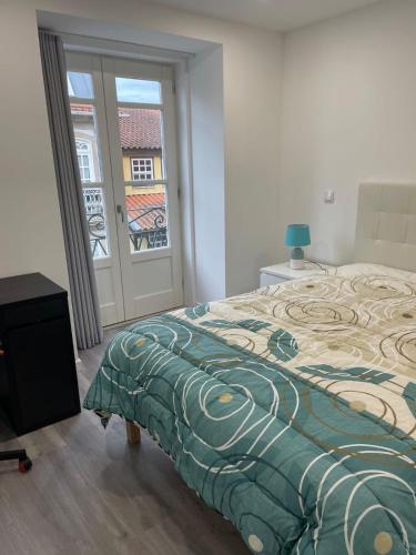 a bedroom with a bed and a door with a window at Ponte Romana in Chaves
