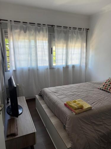 a bedroom with a bed and a window with white curtains at Iluminado y céntrico in San Nicolás de los Arroyos