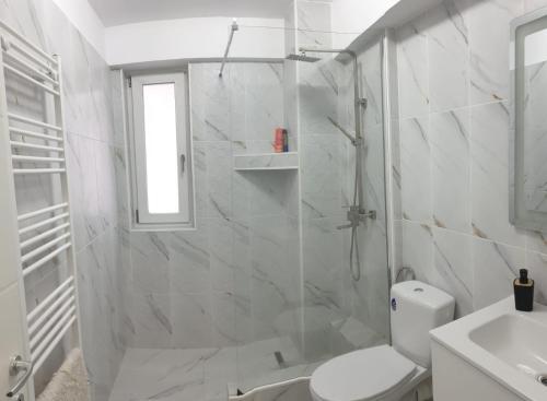 a white bathroom with a shower and a toilet at Apartament in Craiova