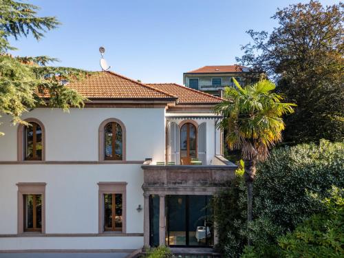 a large white house with a palm tree in front of it at Villa Cedro in Verbania