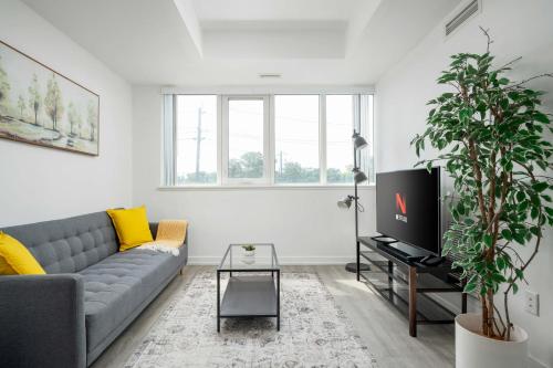 a living room with a couch and a tv at Modern 2 Bed Condo in the Junction+Parking in Toronto