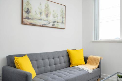 a living room with a gray couch with yellow pillows at Modern 2 Bed Condo in the Junction+Parking in Toronto