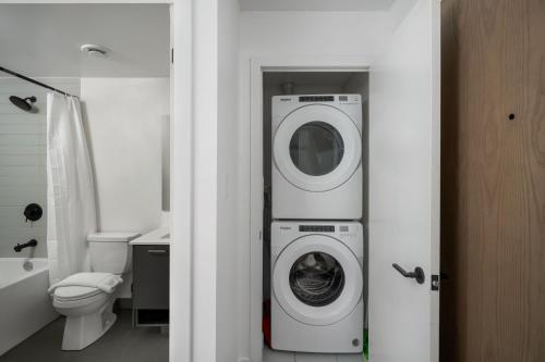 a bathroom with a washing machine and a toilet at Modern 2 Bed Condo in the Junction+Parking in Toronto