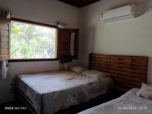 a small bedroom with two beds and a window at Chalés do Valle - Arraial D'ajuda in Porto Seguro