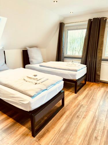 two beds in a room with wooden floors and a window at Hotel Schneider Hof - Self-Check-In by RG Living in Bad Salzuflen