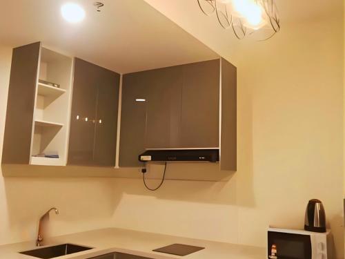 a kitchen with stainless steel cabinets and a microwave at ImpianKU MetaStay KL in Seri Kembangan
