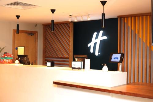 a reception desk with a cross painted on the wall at Holiday Inn Basingstoke by IHG in Basingstoke