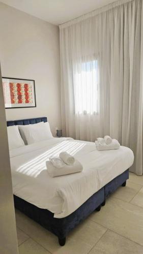 a bedroom with a large bed with two towels on it at 1BR Serviced Apt with Pool & Premium Amenities in Oroklini
