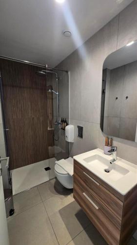 a bathroom with a sink and a toilet and a mirror at 1BR Serviced Apt with Pool & Premium Amenities in Oroklini
