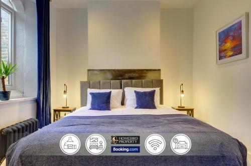 a bedroom with a large bed with blue pillows at Large 6BDR House By Homebird Property Management Short Lets & Serviced Accommodation Leeds With Secured Parking & Garden Area in Leeds