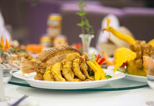 a plate of food on a table with plates of food at Muong Thanh Grand Quang Tri Hotel in Quang Tri