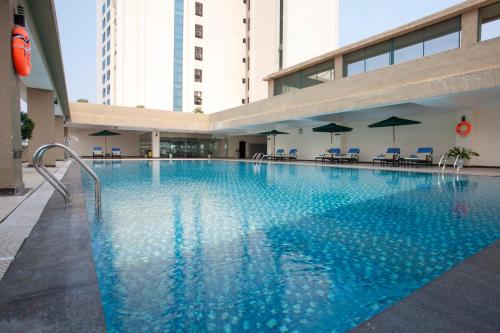 a large swimming pool in a building with chairs and umbrellas at Muong Thanh Grand Quang Tri Hotel in Quang Tri
