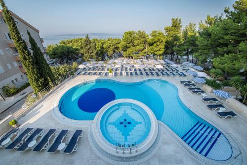 an overhead view of a large swimming pool with lounge chairs at Hotel Horizont in Baška Voda