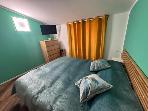 a bedroom with a green bed with two pillows at Attico Vicky in Porto Azzurro