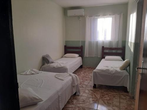 a room with three beds and a window at Kuawit Hotel in Aragarças