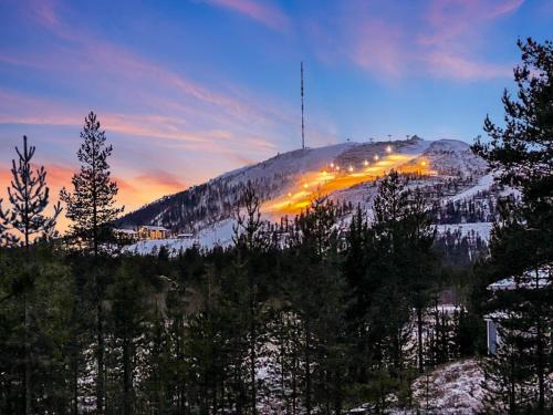 a snow covered mountain with trees and lights on it at Holiday Home Lumomarja by Interhome in Pyhätunturi