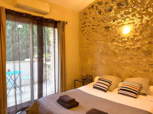 a bedroom with a bed and a large window at Logis Hotel Restaurant L'Esquielle in Saint-Géniès-de-Malgoirès