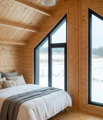 a bedroom with a large bed and large windows at Domki Lubikowo in Przytoczna 