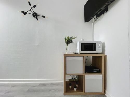 a table with a microwave and a tv on a wall at Le Petit Jules in Dijon