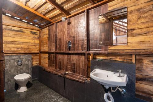 a bathroom with wooden walls and a sink and a toilet at Blue Corner Beach Huts & Restaurant in Benaulim