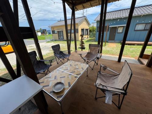 a patio with a table and chairs and a house at Sunny side story hotel 九十九里 in Kujukuri